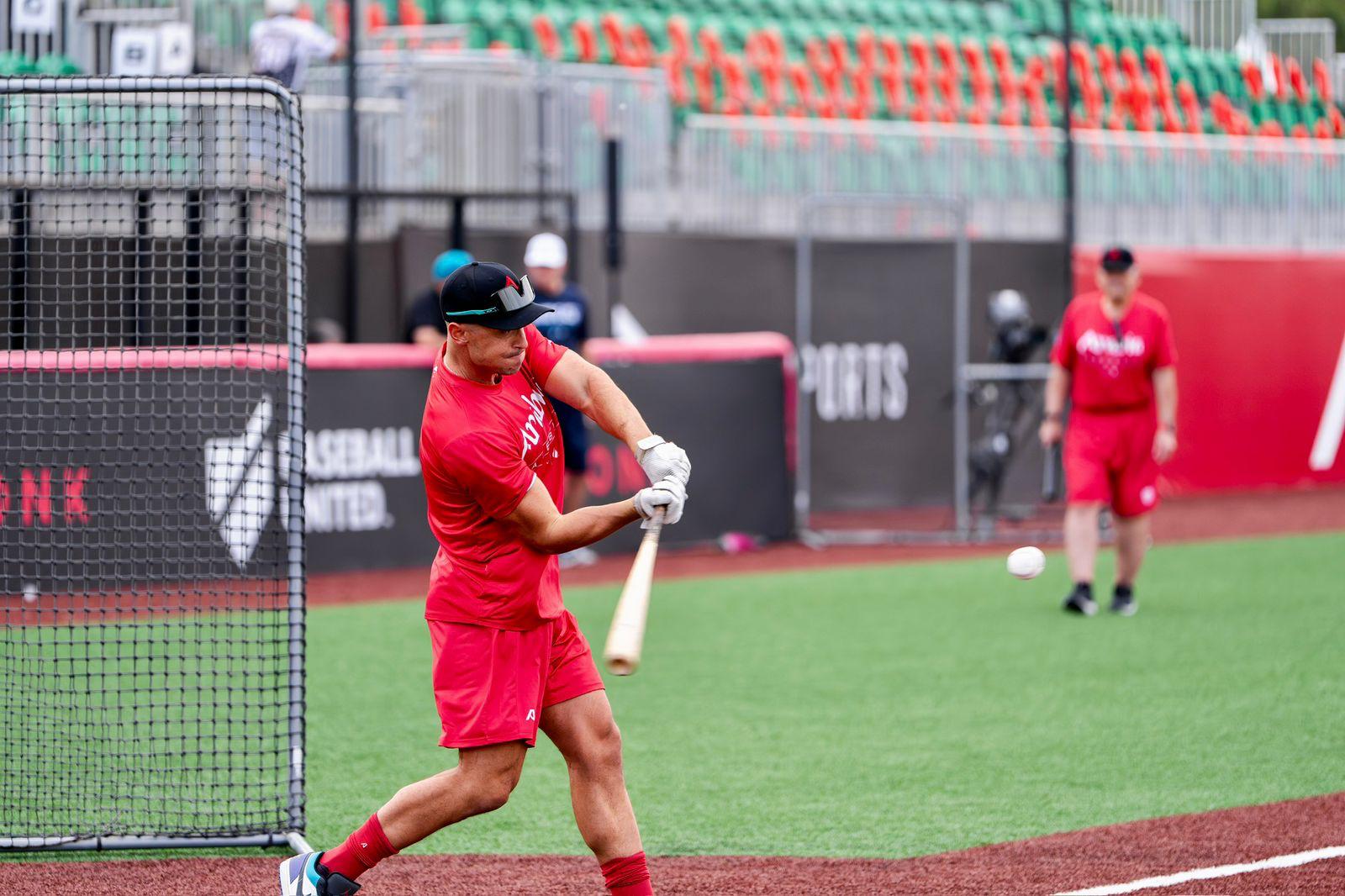 Chris hitting at Baseball United Ballpark in red Arabia Wolves kit
